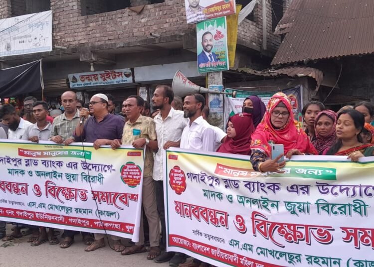 পাইকগাছার নতুন বাজার এলাকায় অনলাইন জুয়া ও মাদকবিরোধী মানববন্ধনে ব্যানার-ফেস্টুন নিয়ে বিভিন্ন শ্রেণি-পেশার মানুষের অংশগ্রহণ।
